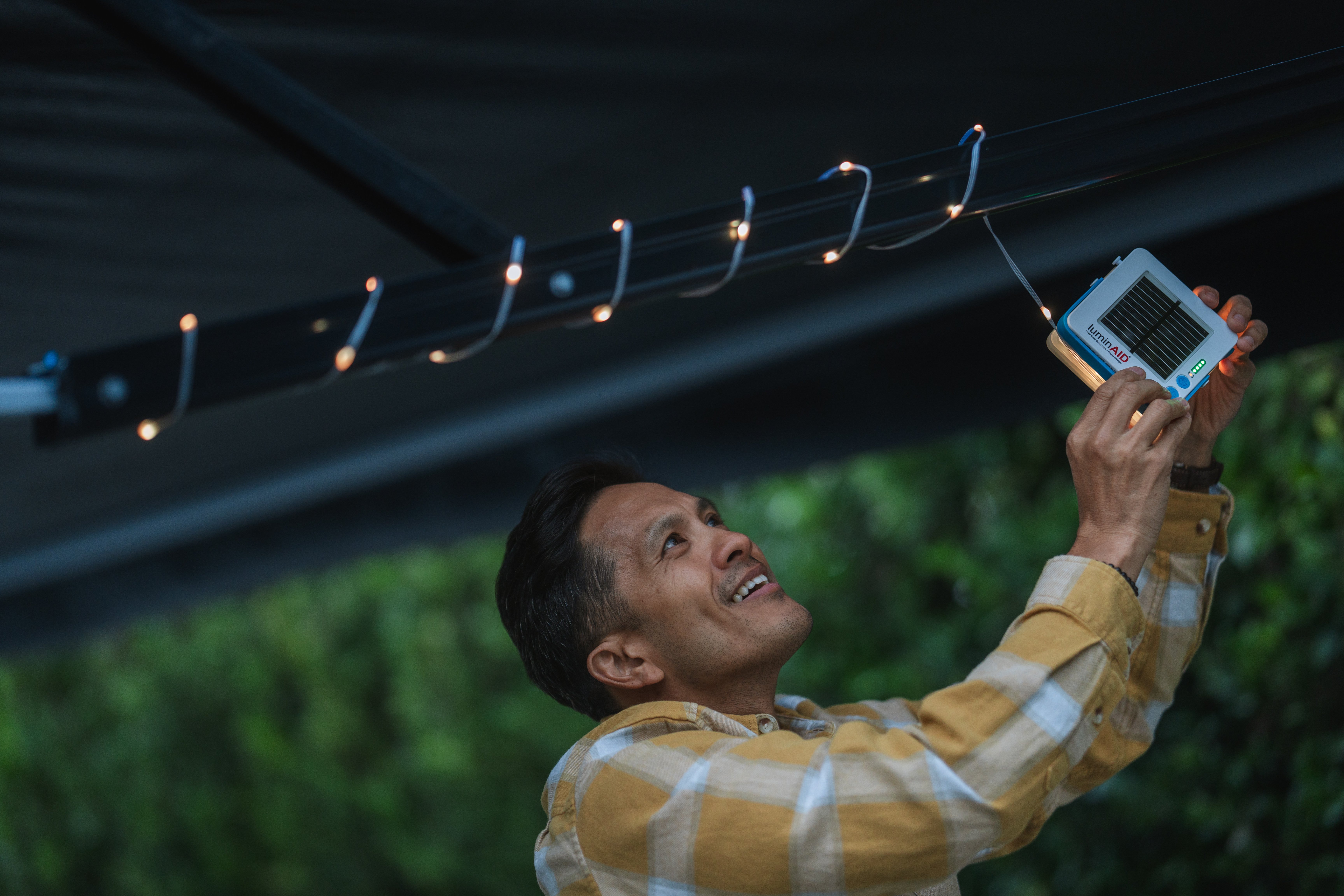 Man hanging solar string lights up on tent