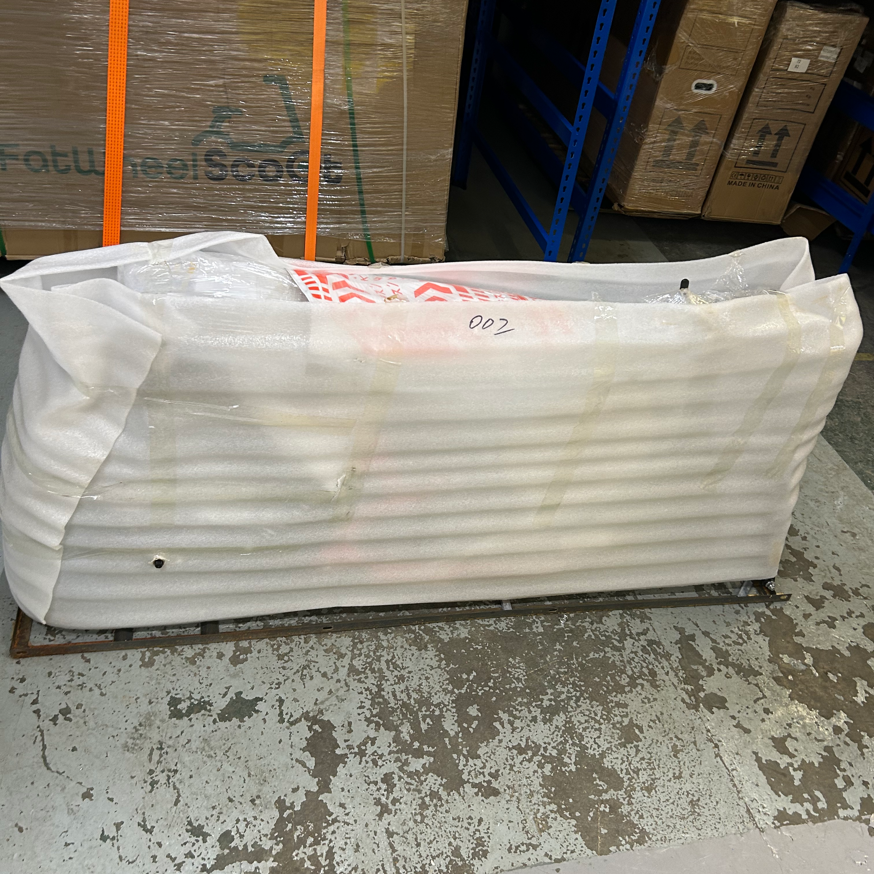 White foam wrapping on a concrete floor with cardboard boxes stacked in the background