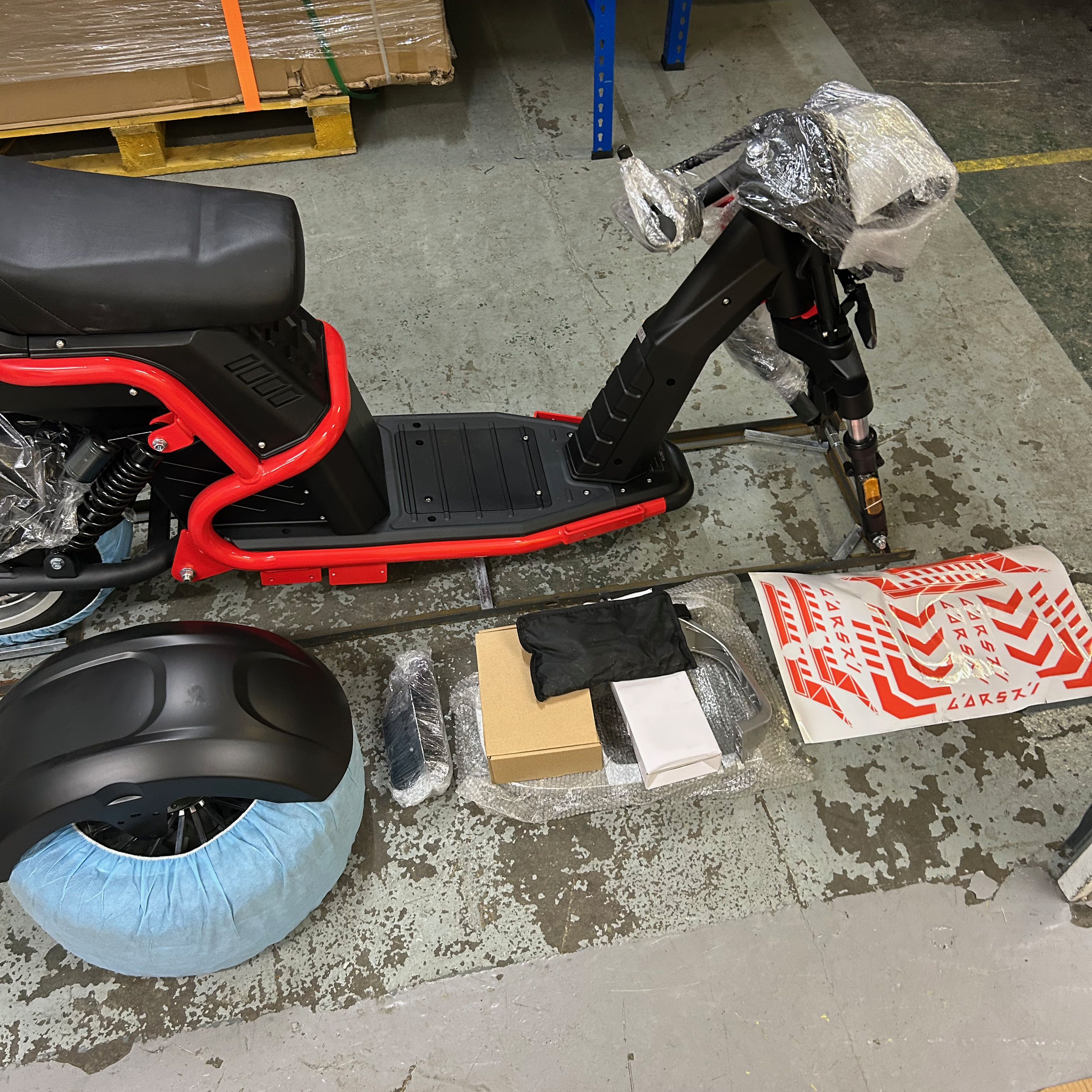 Red and black scooter on a concrete floor with components around