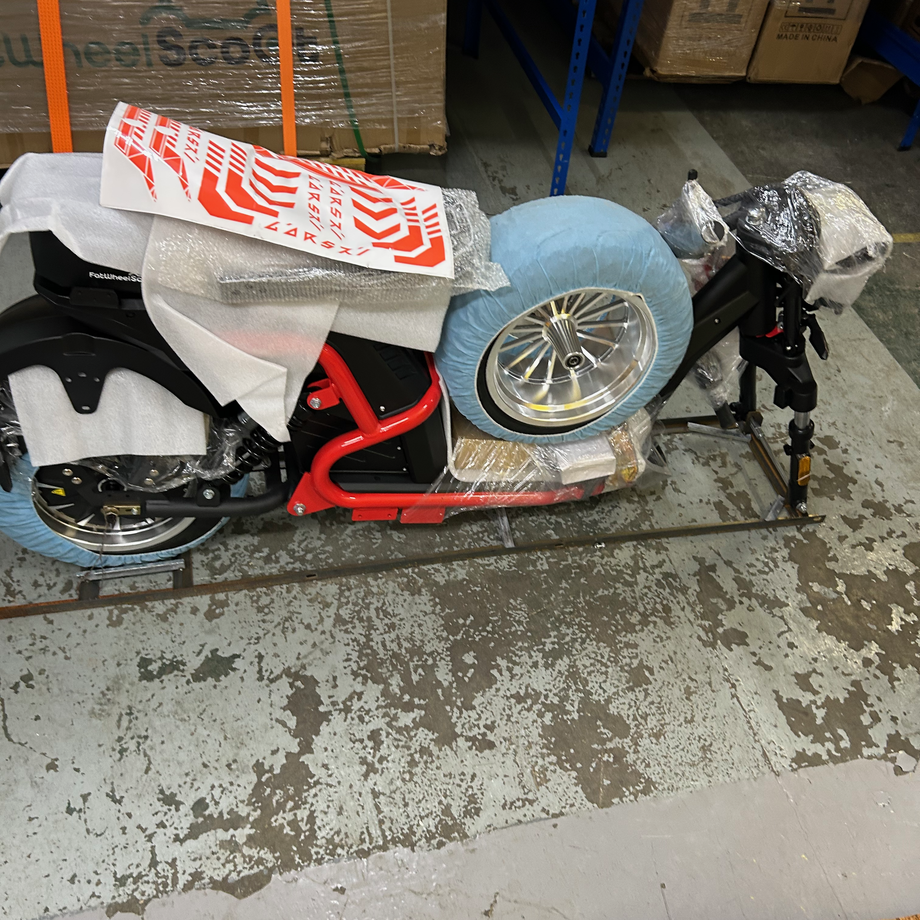 Disassembled scooter with a wheel on a concrete floor in a warehouse setting
