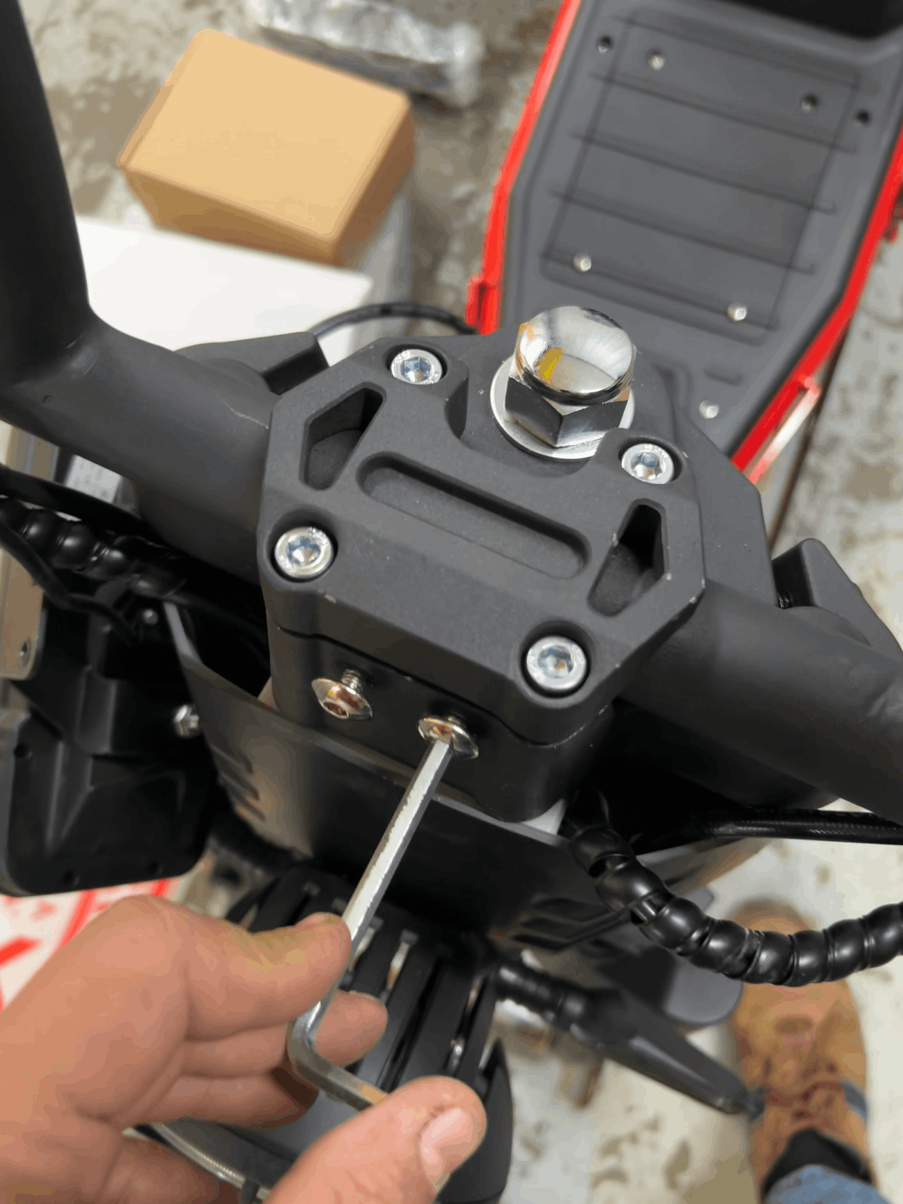 Close-up of a motorcycle handlebar with a hand tightening the screws
