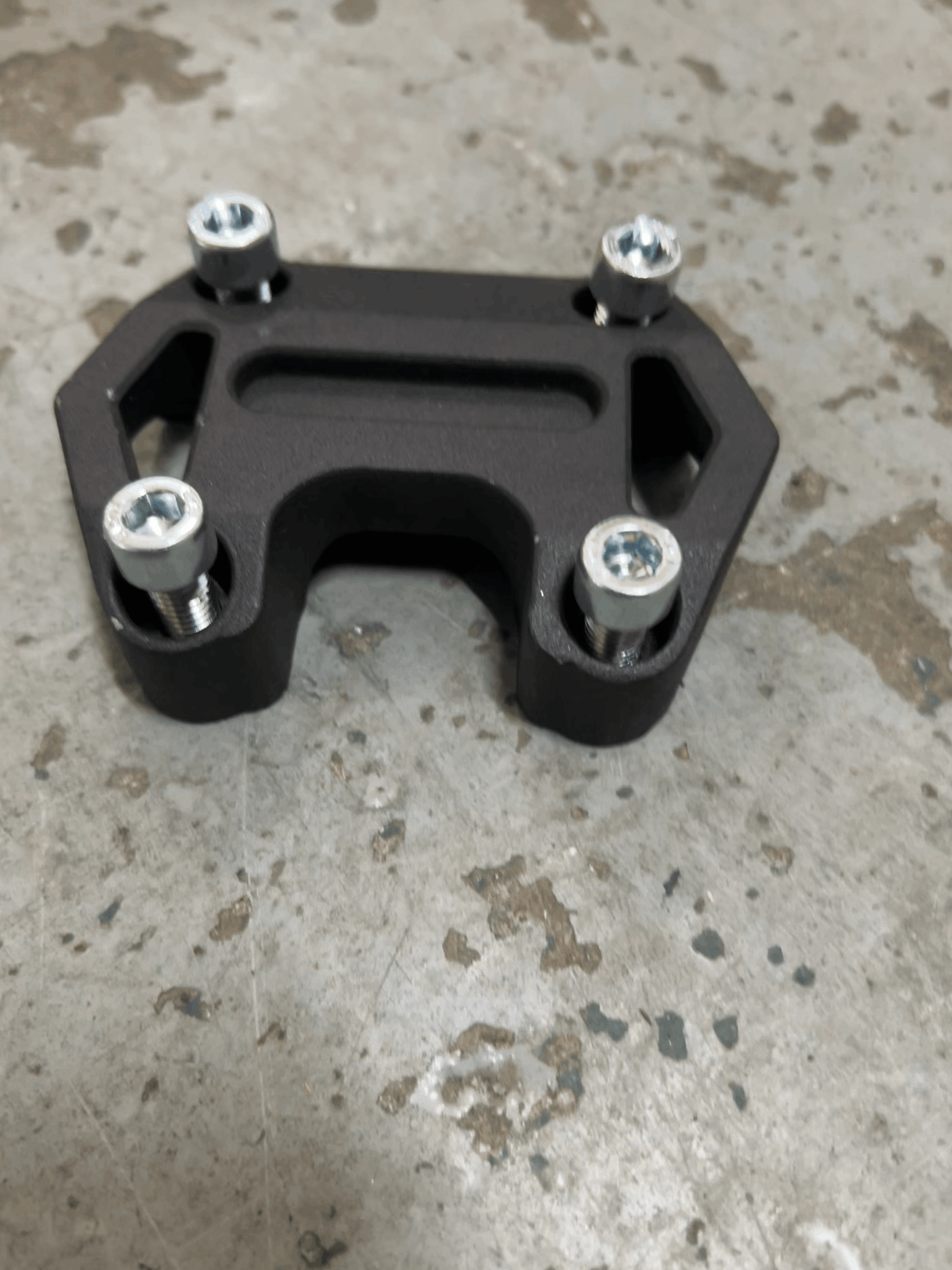 Black metal bracket with screws on a concrete surface