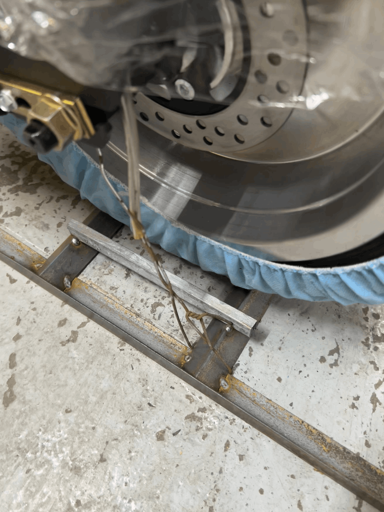 Close-up of a scooter wheel with rotor binded to the metal frame on a concrete floor.