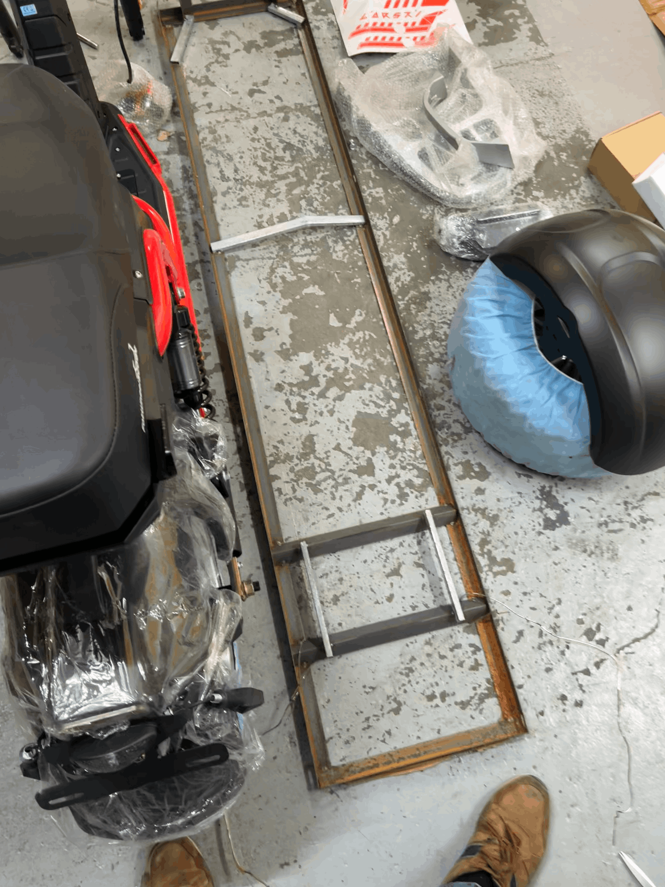 Partial view of a scooter on a concrete floor with parts scattered around.