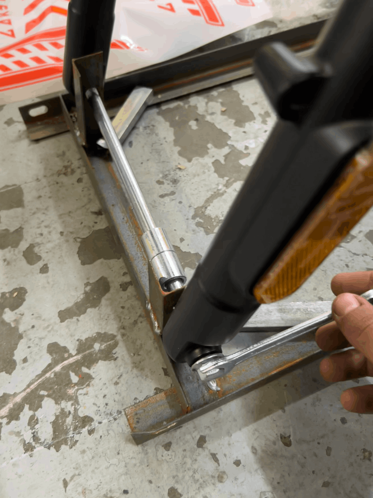 Hand using a wrench on a metal component on a concrete floor