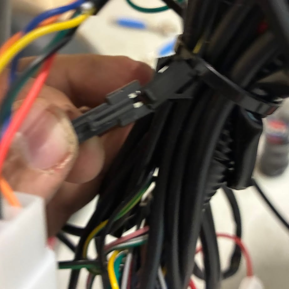 Hand holding a bundle of electrical wires with a black tie-wrap