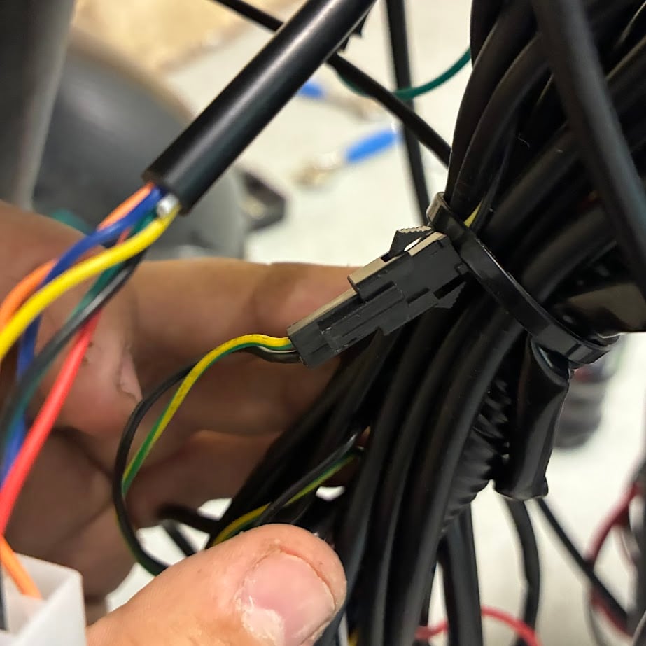 Close-up of hands holding a bundle of colored wires with a black connector.