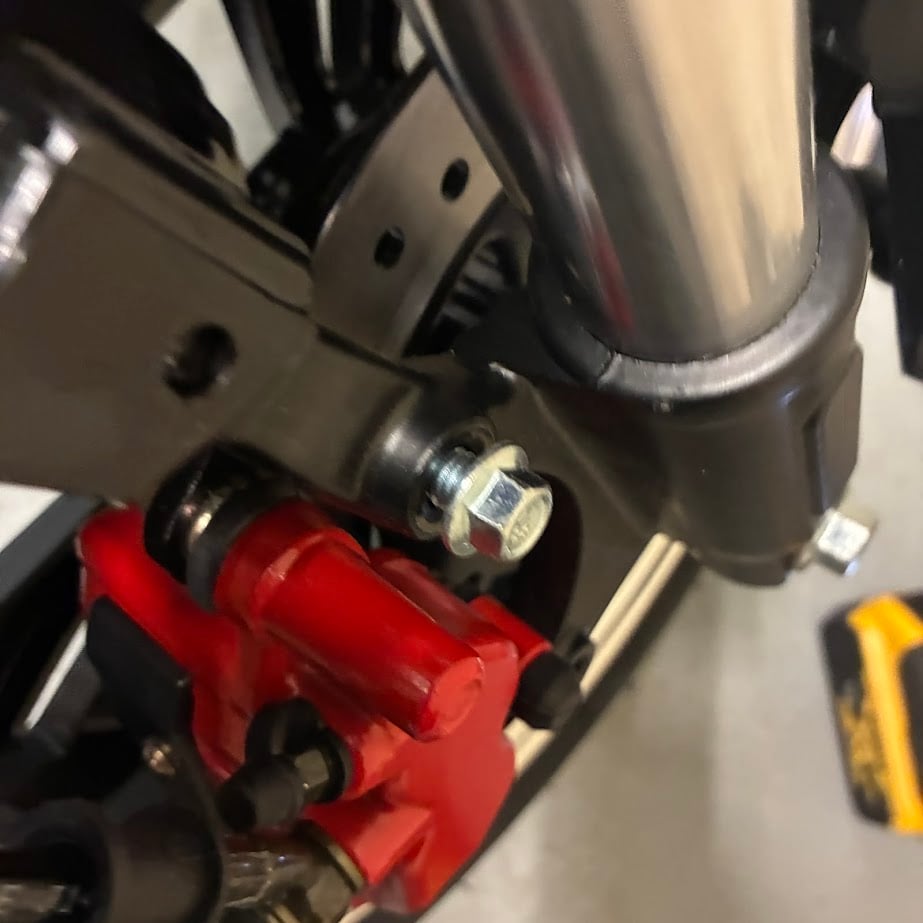 Close-up of a motorcycle's red brake caliper and silver metal components.
