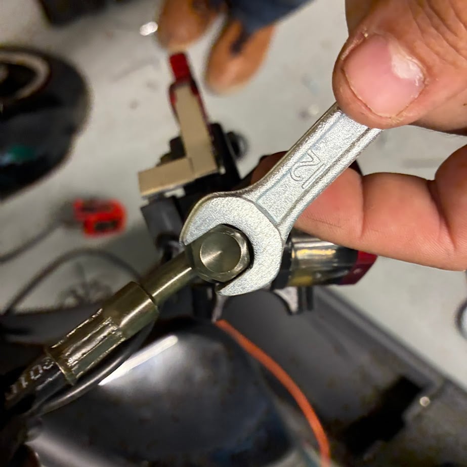 Hand holding a wrench with a blurred workshop background