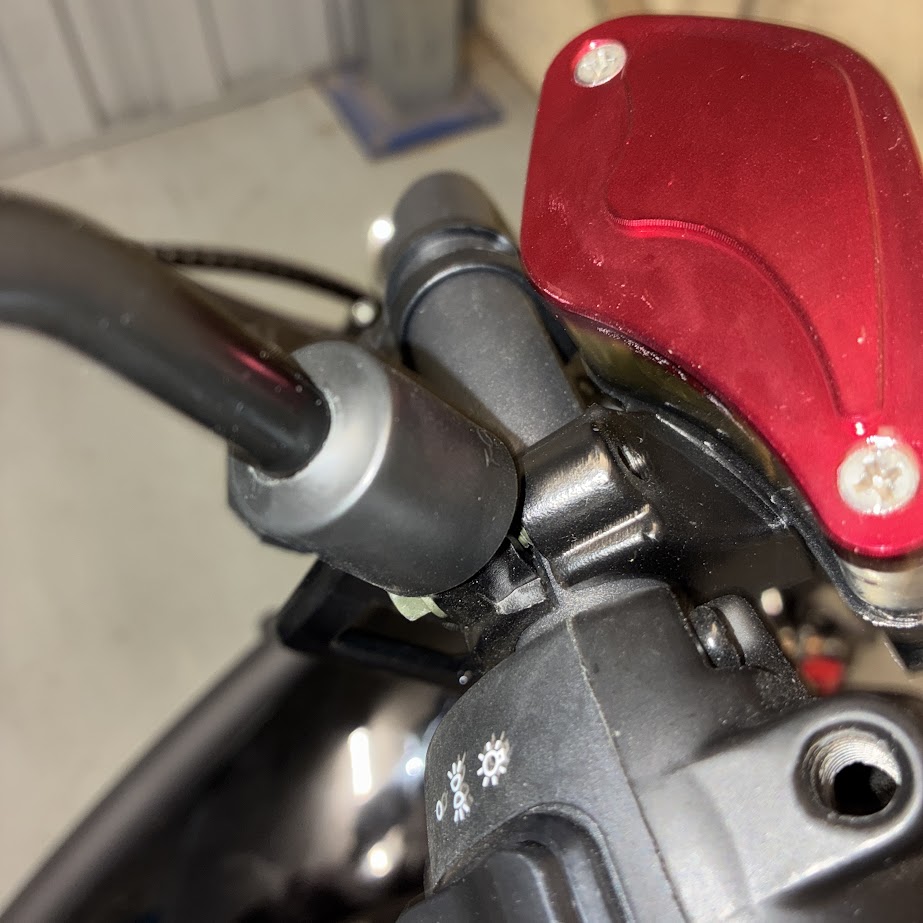 Close-up of a motorcycle handlebar with red brake lever and black grip.
