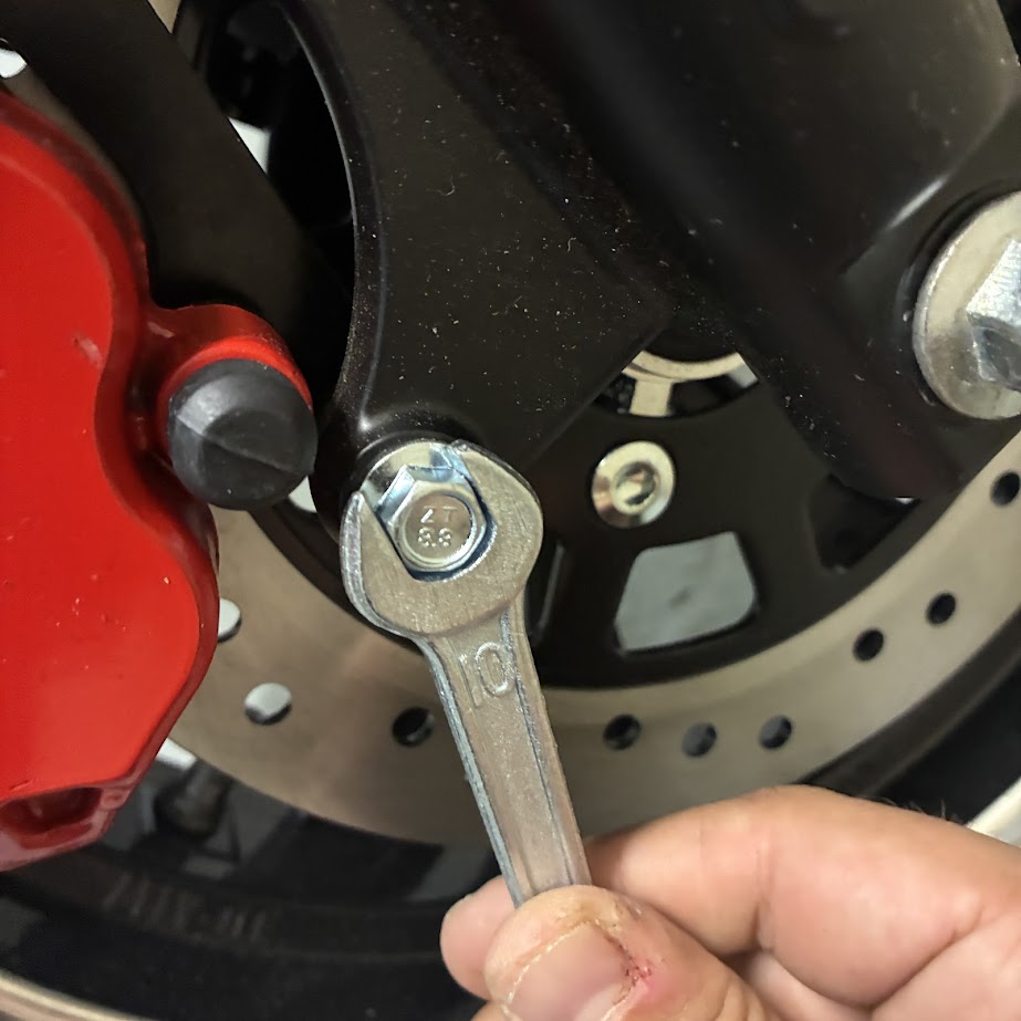 Person using a wrench on a motorcycle brake rotor