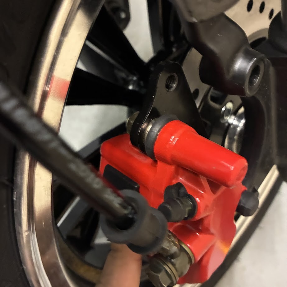 Close-up of a red brake caliper on a motorcycle wheel.