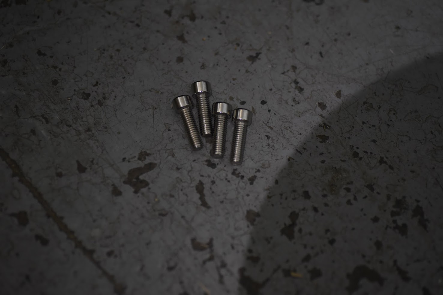 Four metallic screws on a textured dark surface