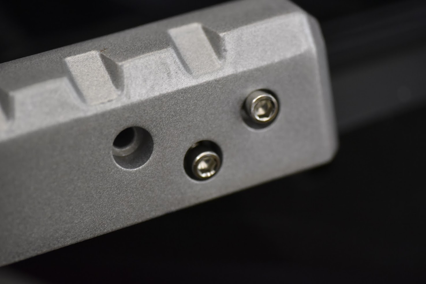 Close-up of a metallic object with textured surface and screws on a dark background