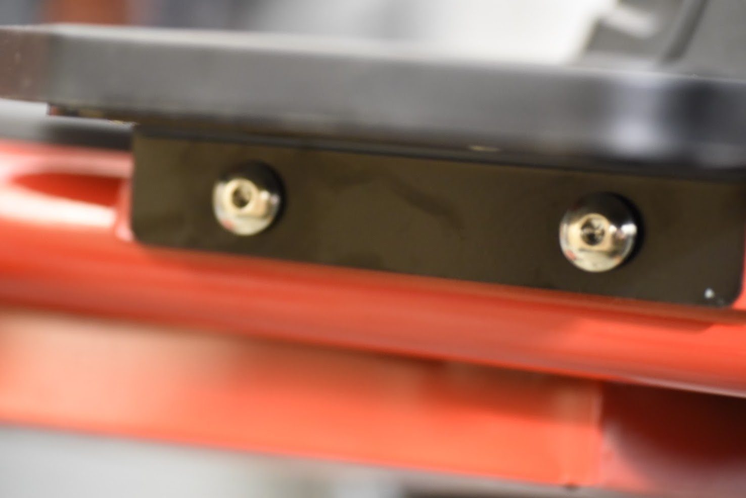 Close-up of a metal bracket with screws on a red and black background