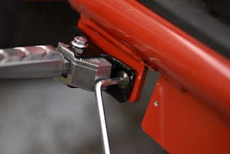 Close-up of a foot peg being tightened to a red metal surface