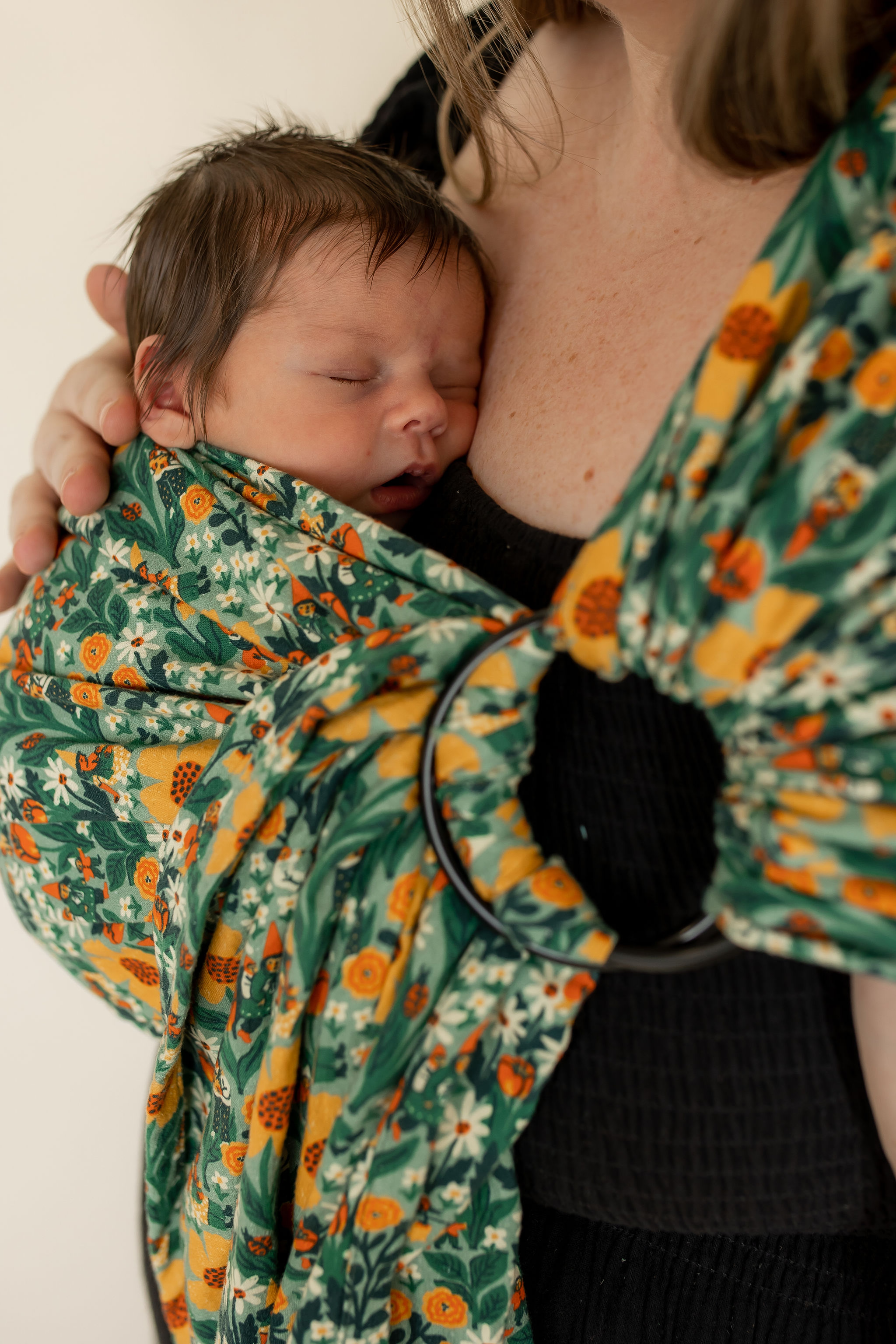 Mother babyweaing her newborn in a sling wrap baby carrier. 
