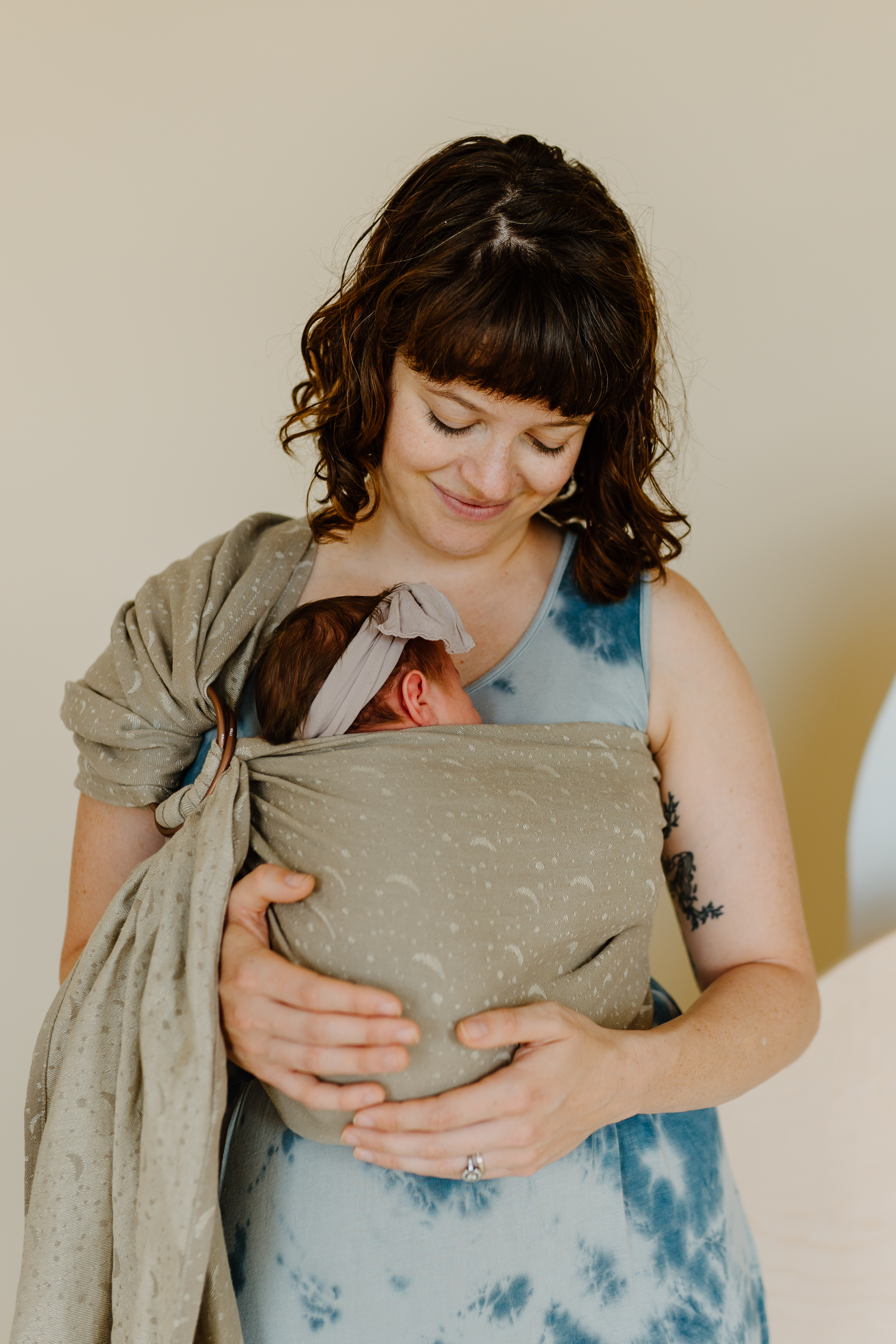 Mother holding newborn in sling baby carrier.